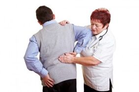 The doctor examines the lower back with osteochondrosis